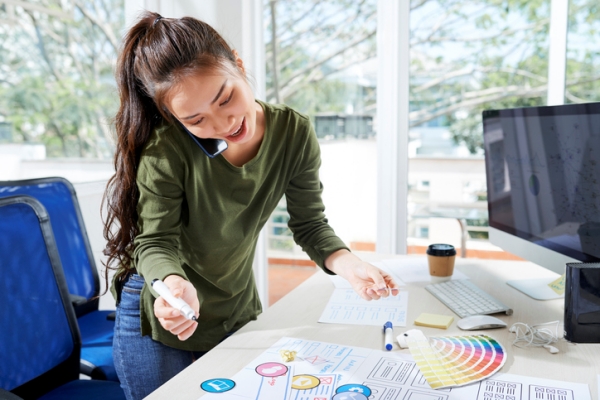 female web designer on phone and looking at design elements